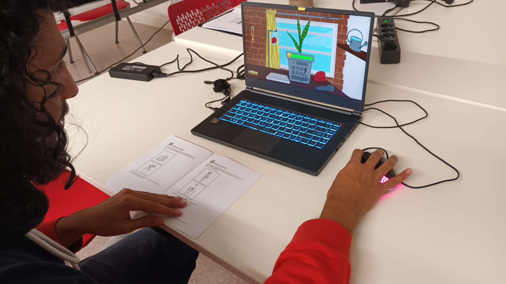 Photographie d'une personne jouant au jeu sur un ordinateur tout en consultant un manuel ouvert devant elle